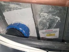 Pipe penetration through a metal-clad duct sealed with fire stopping and a warning label